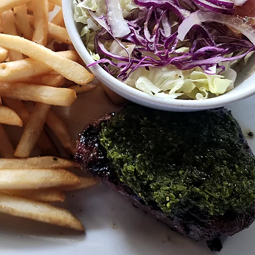 Ribeye steak topped with chimichurri, with fries and a cabbage salad