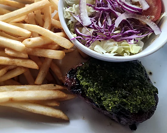Ribeye steak topped with chimichurri, with fries and a cabbage salad