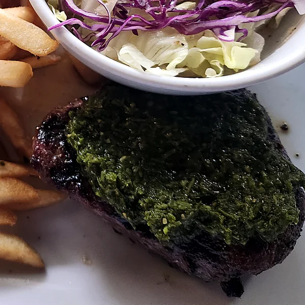 Ribeye steak topped with chimichurri, with fries and a cabbage salad