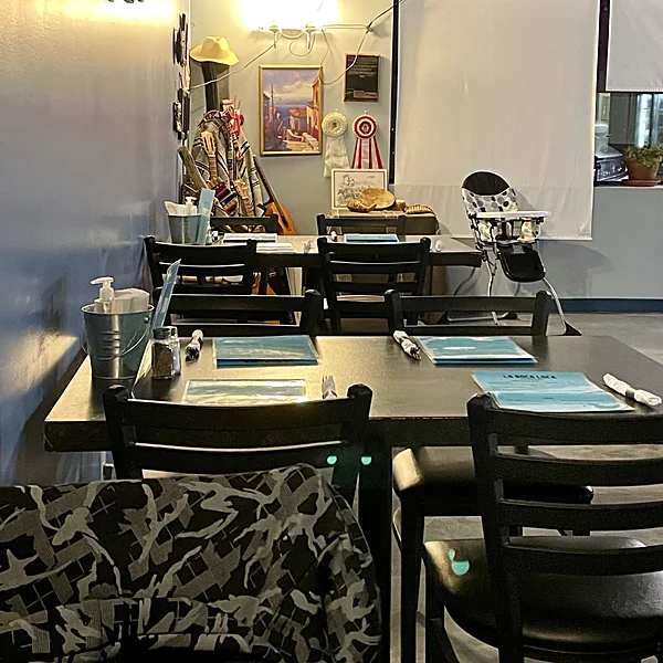 La Boca Loca dining room with dark tables, place settings and framed art