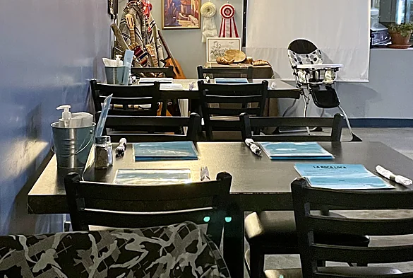 La Boca Loca dining room with dark tables, place settings and framed art